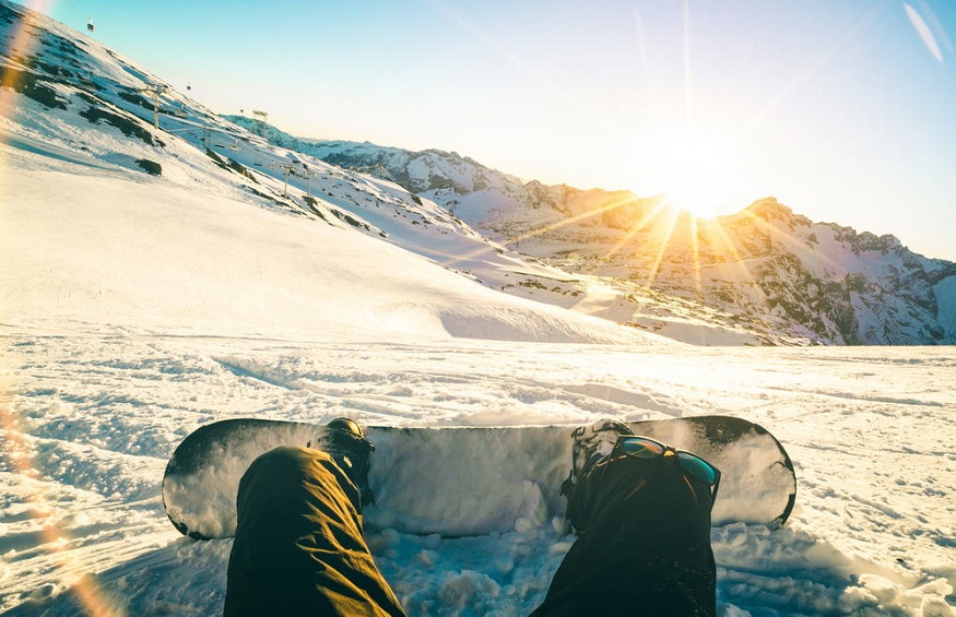 Snowboarder sitting at sunset on relax moment in french alps ski